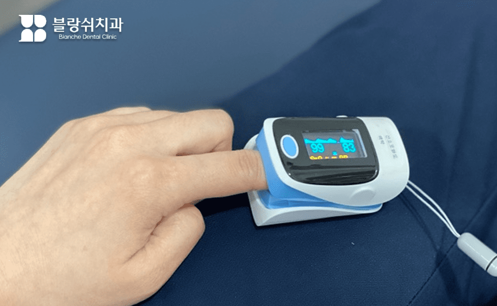 安全な睡眠治療歯科診療のため、患者の指に酸素飽和度測定装置を装着し、リアルタイムで健康状態をチェックするシーン。